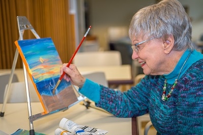 Senior woman learning to paint to improve her brain health