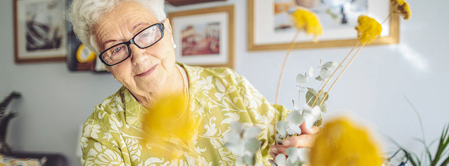 A senior woman arranges yellow flowers