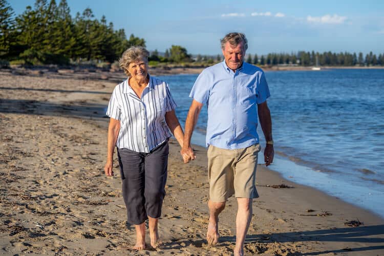 A happy senior couple takes a stroll on the beach.