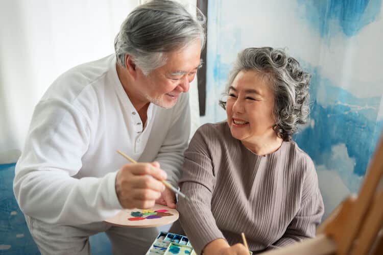 A senior couple enjoy painting together at home.
