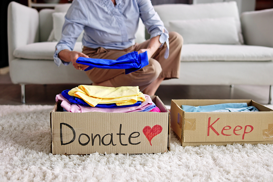 A senior woman declutters using keep and donate boxes.