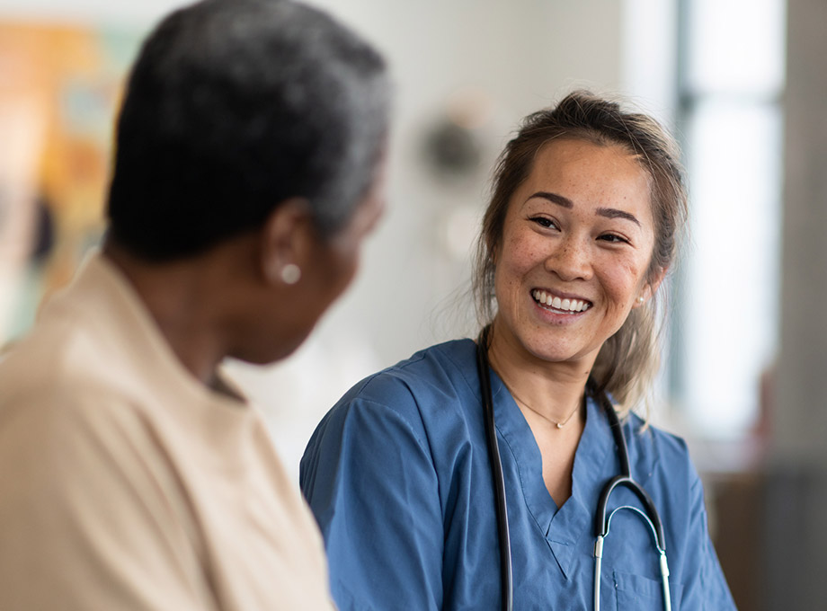 A health care professional smiles and talks with a senior woman