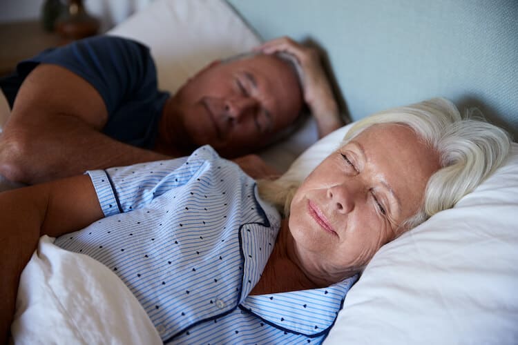 A senior couple sleeping safely and securely in their bed at night.