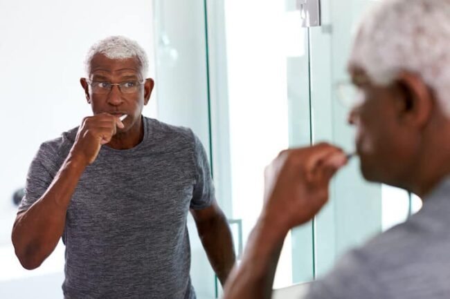 A senior brushing his teeth in order to maintain good hygiene.