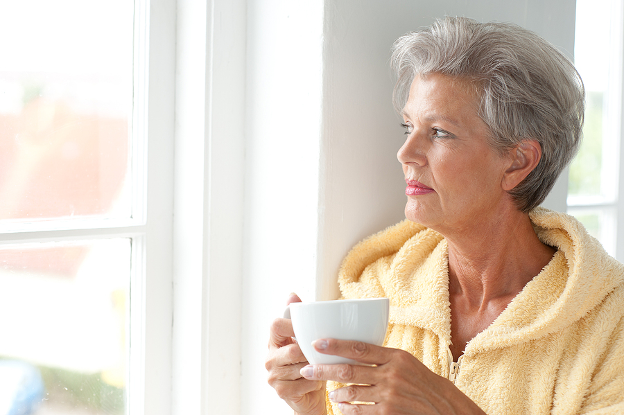 A senior woman drinks coffee.