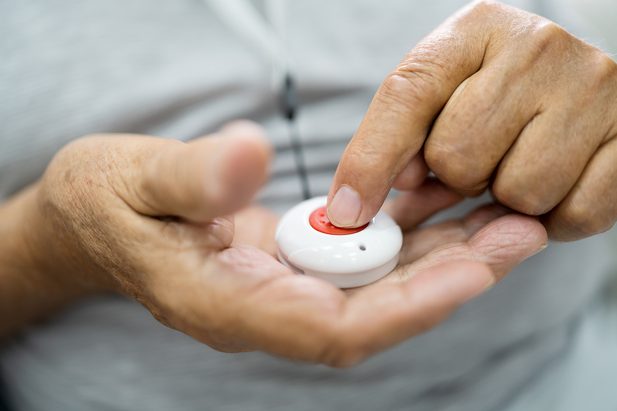 Senior hands pressing a button on a medical alert device