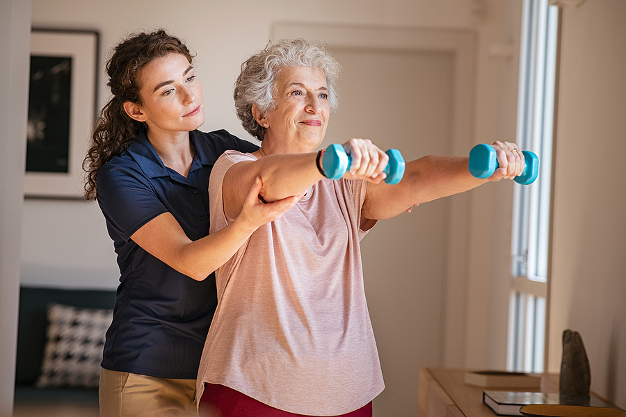 A physical therapist and an older adult woman perform daily physical therapy exercises