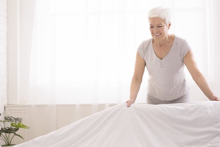 Senior woman staging her home to sell by adding light colors to the living area.