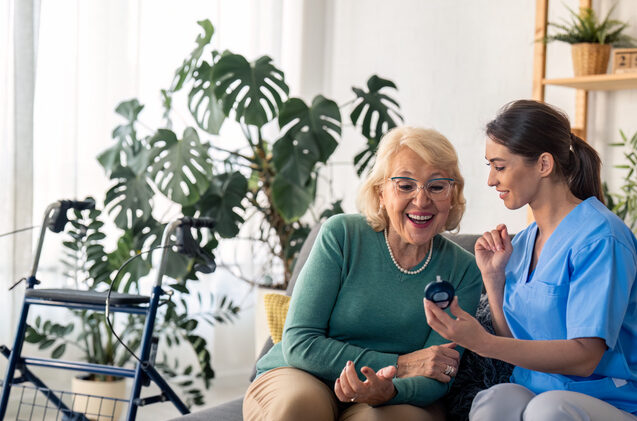 Nurse Helping Check Senior Woman's Blood Sugar