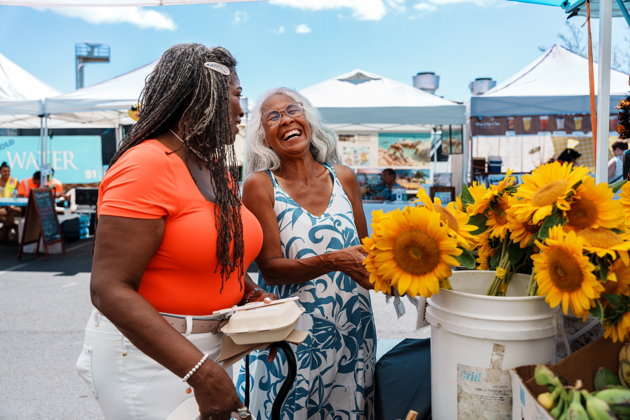 Two senior women on a trip together, exploring a farmers market