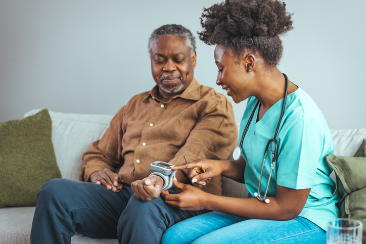 Nurse Checks Senior Mans Blood Pressure, Both Smiling