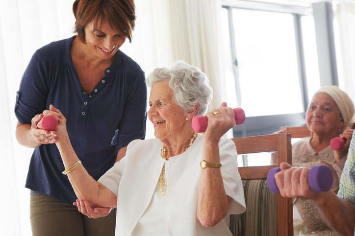 Physical Therapisty Helping Senior Woman with Light Weights