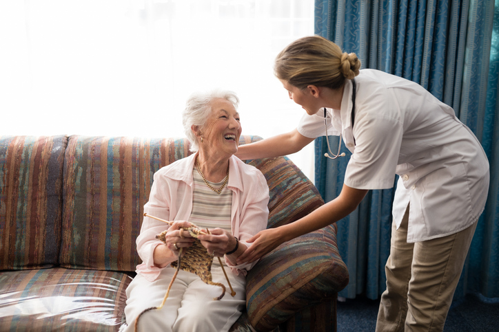 Senior Woman Smiling at Caretaker while Knitting